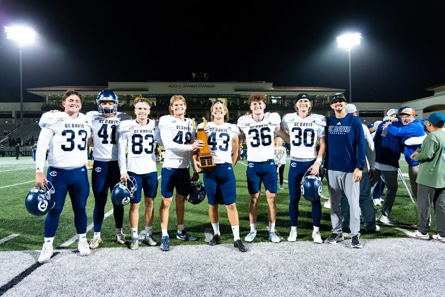 UC Davis football team holding the conference trophy at Alex G. Spanos Stadium